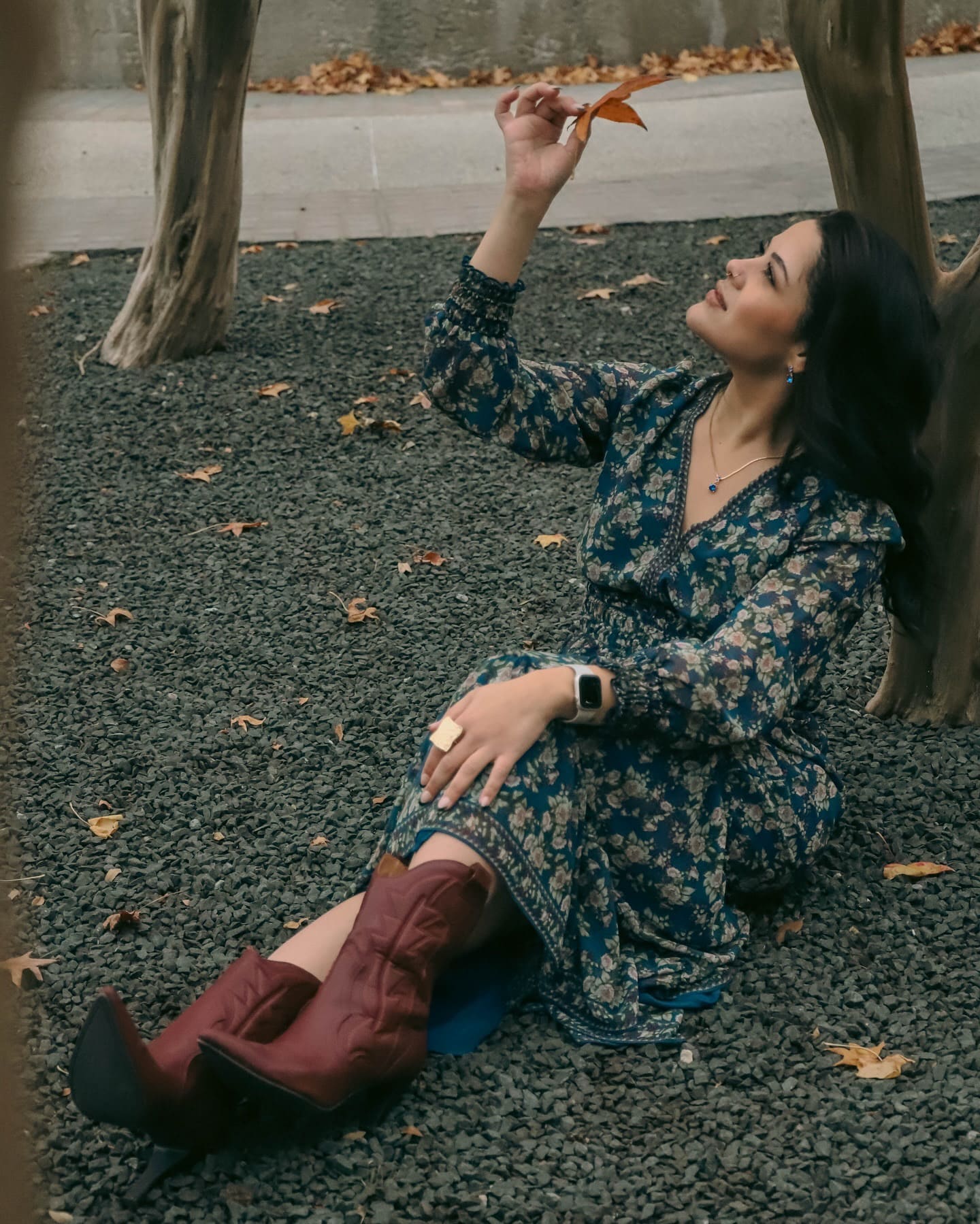 Woman in a floral dress resting among autumn leaves
