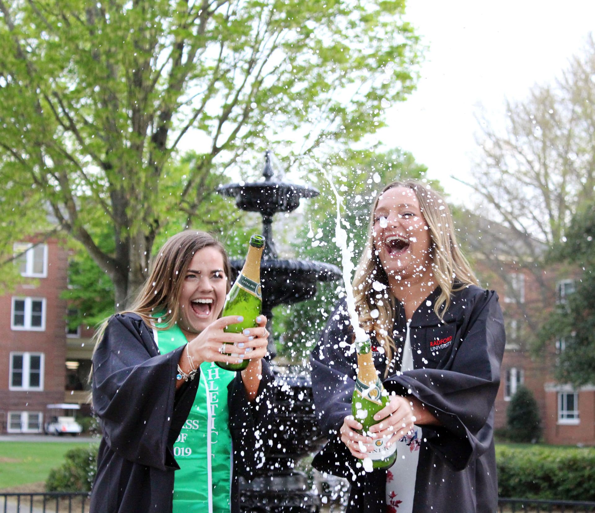 Graduates celebrating beside a fountain with sparkling wine