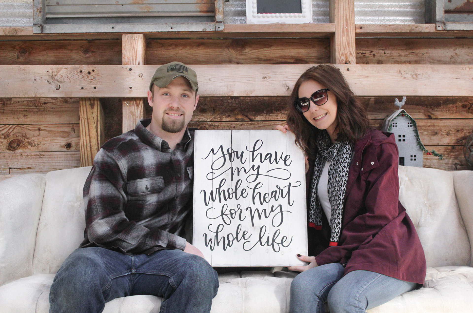 Couple sitting together with a handwritten keepsake sign