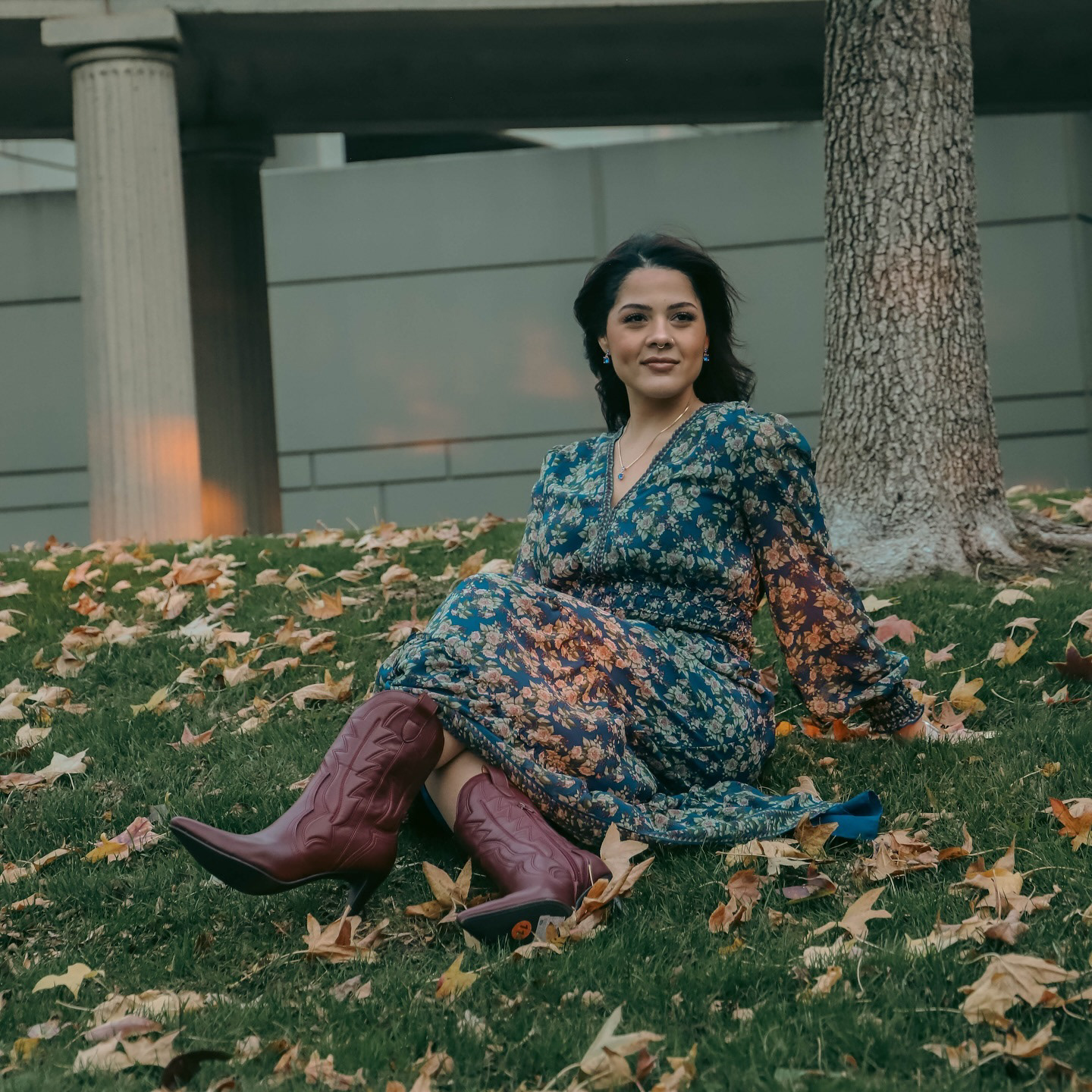 Woman in a floral dress seated on autumn leaf-covered stone steps