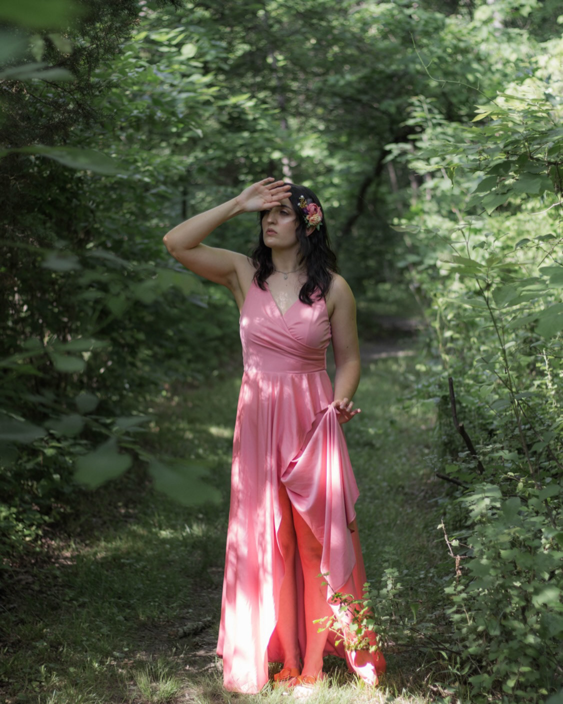 Woman in a pink dress standing among tall trees